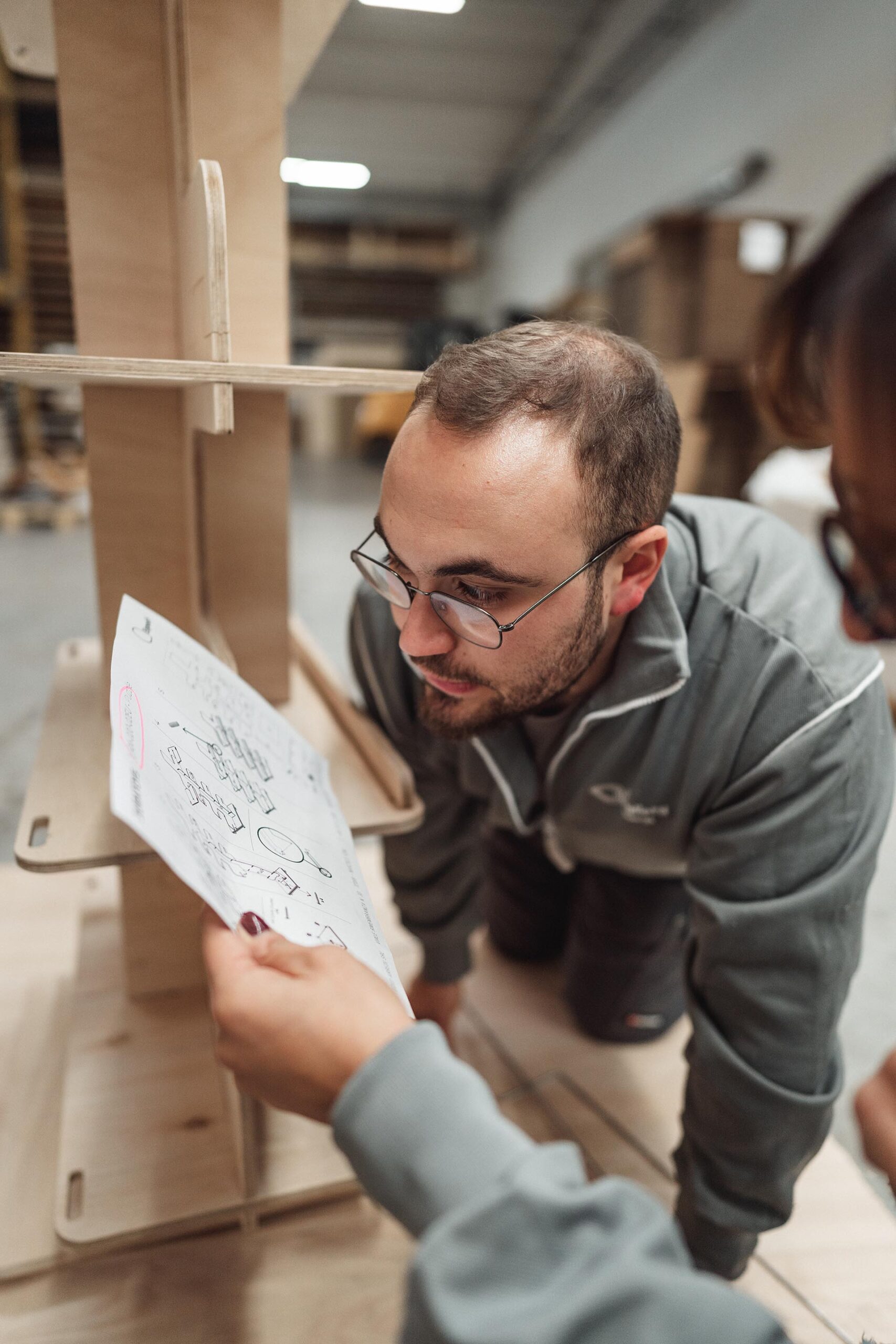 Designer checking a wooden prototype against a sketch